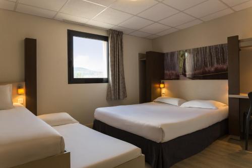 a hotel room with two beds and a window at The Originals City, Hôtel Clermont-Ferrand Sud Aubière in Aubière