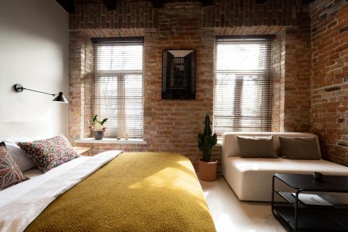 une chambre avec un mur de briques, un lit et un canapé dans l'établissement Hortus Vilnius, à Vilnius