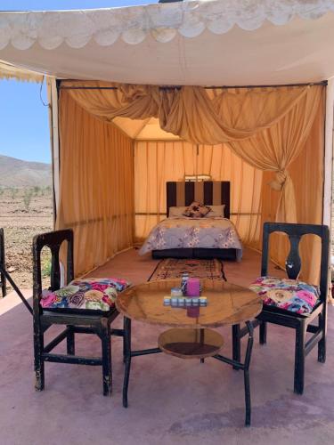 1 dormitorio con 1 cama y 2 mesas y sillas en la casa de othmane en Marrakech
