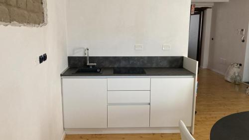 a kitchen with white cabinets and a sink at La Suite Sotto Stelle in Oristano