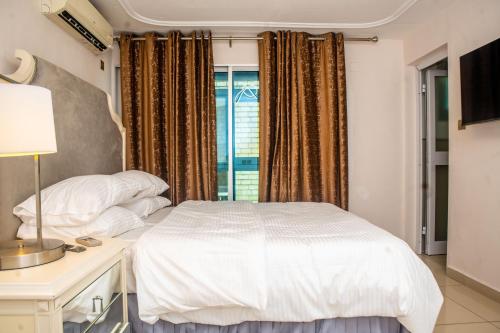 a bedroom with a white bed and a window at Villa Princess Douala Bali in Douala