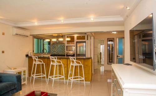 a kitchen and living room with a counter and stools at Villa Princess Douala Bali in Douala