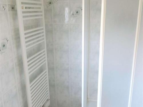 La salle de bains est pourvue d'une douche blanche et d'étagères blanches. dans l'établissement Maison bretonne avec jardin clos, centre Perros-Guirec, proche plage et commerces - FR-1-368-285, à Perros-Guirec