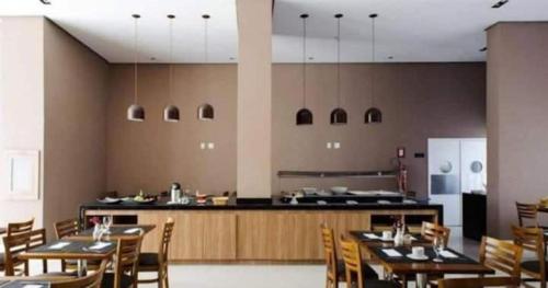 Un restaurante con mesas y sillas y una cocina. en Centro de Convenções Riocentro - O melhor para mais de 2 hóspedes - Shows Rio de Janeiro, RioStay Flat - Cidade do Rock - Jeunesse Arena - Parque Olimpico - Apartamento Duplo Completo, en Río de Janeiro