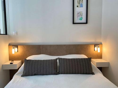 - une chambre avec un lit avec deux oreillers et deux tables dans l'établissement Charmant T1 avec balcon, climatisation, et parking - Face Parc Charles de Gaulle - Balaruc-les-Bains - FR-1-553-147, à Balaruc-les-Bains