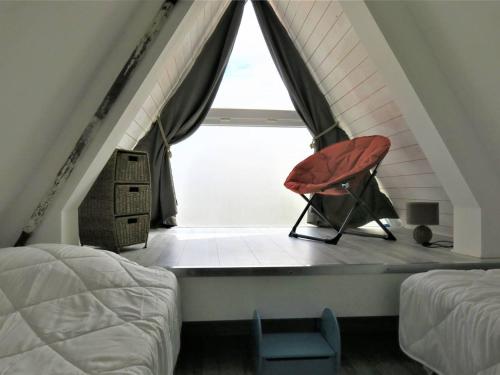 een rode stoel voor een raam op zolder bij Maison Perros-Guirec, 3 pièces, 4 personnes - FR-1-368-301 in Perros-Guirec
