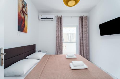 1 dormitorio con 1 cama grande y TV en Casa Albastra Rooms & Suites en Porto Heli