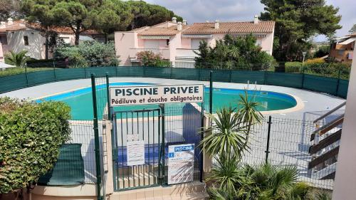 une clôture avec un panneau en face d'une piscine dans l'établissement Appartement 2 pièces mezzanine avec piscine, au Cap d'Agde