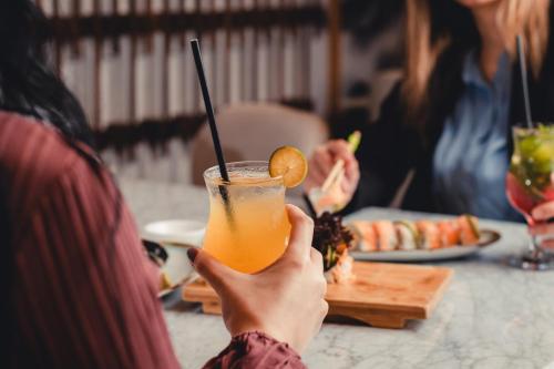 a person holding up a drink with a slice of orange at Holiday Inn Kuwait by IHG in Kuwait