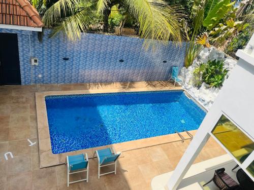 uma vista sobre uma piscina com duas cadeiras azuis em Chambre SDB simple avec accès piscine em Sali Poulang