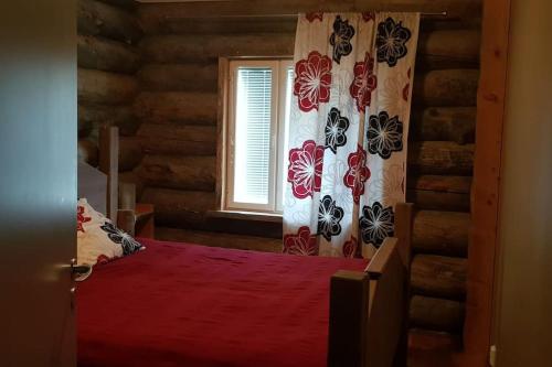Schlafzimmer mit einem roten Bett und einem Fenster in der Unterkunft Villa Laattamaja - High quality genuine loghouse in Ylläsjärvi