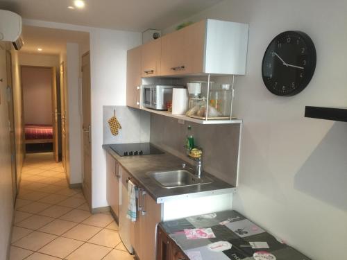 une cuisine avec un évier et une horloge murale dans l'établissement BEAU STUDIO CLIMATISE PROXIMITE PORTS ET PLAGES, à La Ciotat