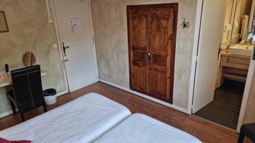 a bedroom with a bed and a wooden door at Logis Hôtels Le Saint Marc in Mollans-sur-Ouvèze