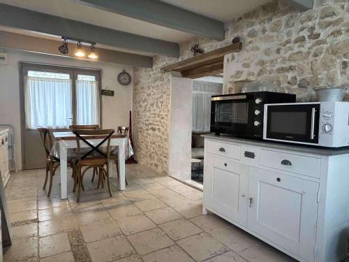 - une cuisine avec une table et un four micro-ondes dans l'établissement Maison de charme rénovée 4 pers., Saint-Georges-d'Oléron, proche plage, Wifi, parking gratuit - FR-1-246A-85, à Saint-Georges-dʼOléron