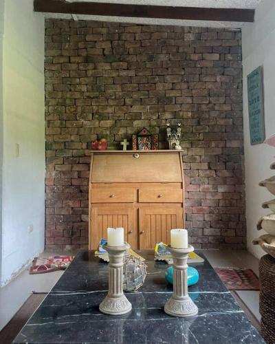 una habitación con una pared de ladrillo y dos velas en una mesa en Casa Pachacamac 'Pan de Azúcar', en Pachacámac