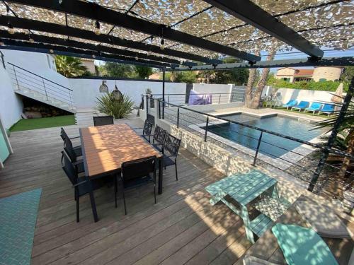 un patio avec une table et des chaises et une piscine dans l'établissement Haut de villa, avec piscine tout confort, 2km de la plage., à La Seyne-sur-Mer