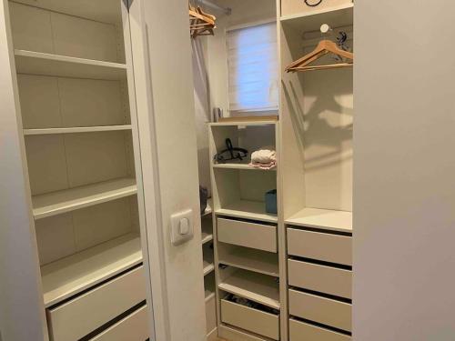 Elle comprend un dressing avec des étagères blanches et une fenêtre. dans l'établissement Haut de villa, avec piscine tout confort, 2km de la plage., à La Seyne-sur-Mer