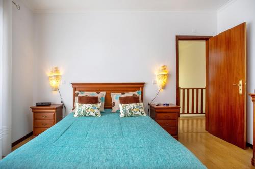um quarto com uma cama grande e uma colcha azul em Casa da Cândida na Nazaré