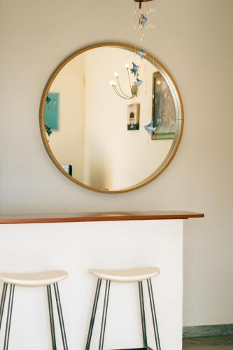 a round mirror on a wall with two stools at Le Case della Costa - Appartamento Capri in Maiori