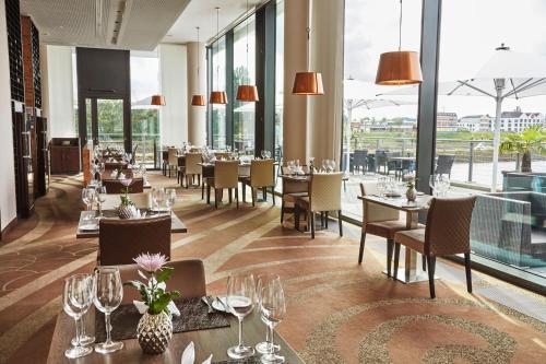 a restaurant with tables and chairs and windows at Steigenberger Hotel Bremen in Bremen