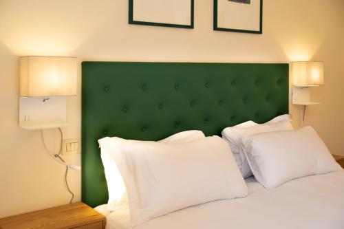a bed with a green headboard and white pillows at Velabro Luxury Loft in Rome