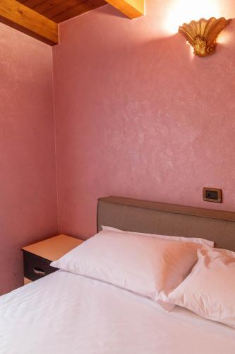 a bedroom with a white bed and a pink wall at Angoni Villa in Durrës
