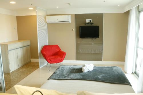 a bedroom with a bed and a red chair at Flat no Brasília Lider, 14º Andar in Brasília