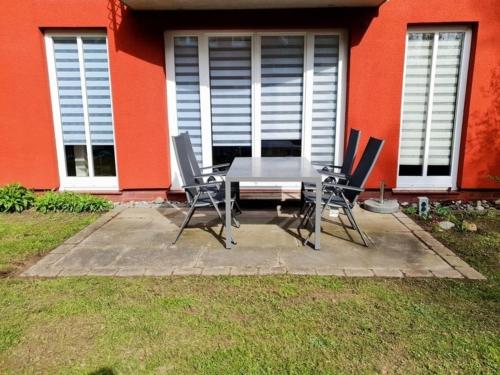 a table and chairs in front of a red house at Ferienwohnung Mönchgut II in Middelhagen