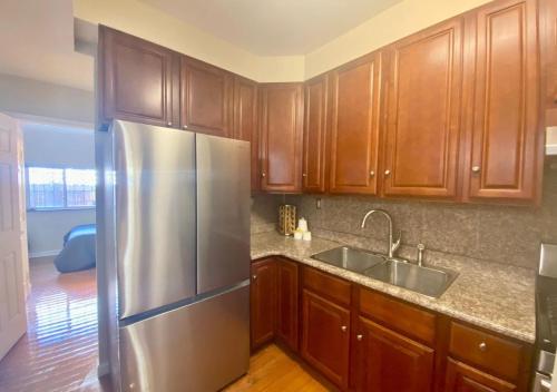 a kitchen with wooden cabinets and a stainless steel refrigerator at Historic Townhouse Oasis with En-suite Bathroom in Philadelphia