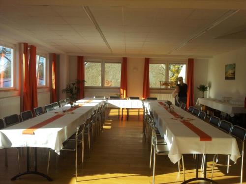 a large room with long tables and chairs and a woman at Sefano Low Budget Hotel in Nossen
