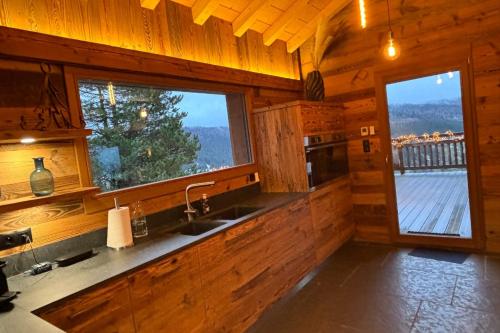 a kitchen with a sink and a window in a cabin at Chalet du Paradis Blanc in La Bresse