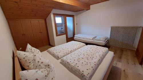 Habitación pequeña con 2 camas y ventana en THOMASERHOF APARTMENT AGRITURISMO en Redagno