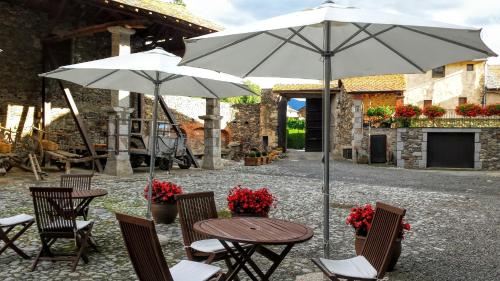 a table and chairs with an umbrella in a courtyard at Hotel Bernat de So in Llivia