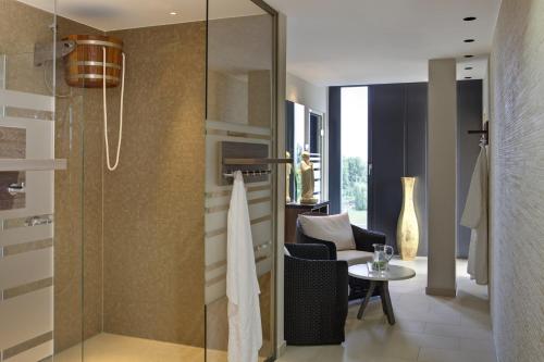 a bathroom with a glass shower with a table at Steigenberger Hotel Bremen in Bremen
