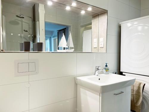 a white bathroom with a sink and a mirror at Apartment Oase am Meer, Am Alten Deich 18 in Dangast