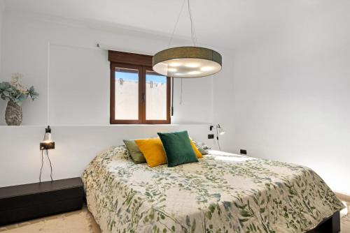 um quarto com uma cama com almofadas amarelas e verdes em Somni em Xàbia
