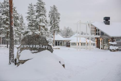 um quintal coberto de neve com um edifício e árvores em HUNURIJÄRVI RESORT***** em Härmä