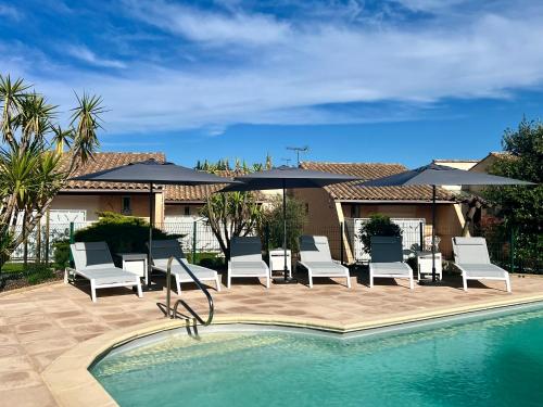 a pool with chairs and umbrellas next to a house at Mélisande au pays des orjouliers in Saint-Jean-de-Fos