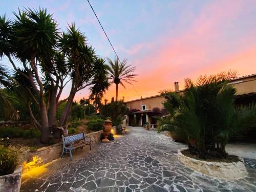 a patio with a bench and palm trees at sunset at FincaOase-Can-Negre-Son-Macia-App-Petit in Son Macia