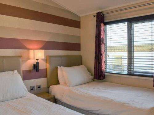a hotel room with two beds and a window at Victory Lodge 2 Bedroom - Sleeps 6 - Bron-Y-Wendon Holiday Park in Llanddulas