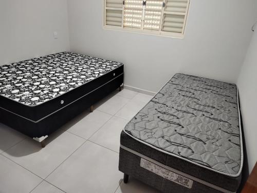two twin beds in a room with a mattress at Casa de Temporada Isaura in Olímpia