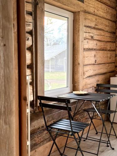 a table and two chairs in a room with a window at PLŪSME Restart House in Lielstraupe