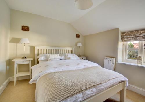 a bedroom with a white bed and a window at Rose Cottage in Sedgeford