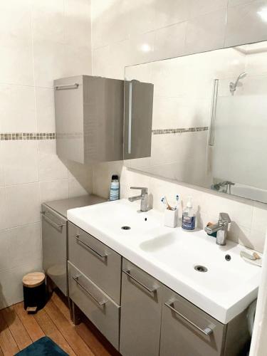 La salle de bains est pourvue d'un lavabo blanc et d'un miroir. dans l'établissement Villa de 4 chambres avec jardin clos et wifi a Elancourt, à Élancourt