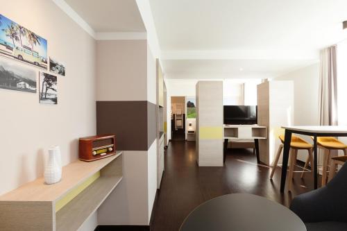 a living room with a table and a television at Vienna House Easy by Wyndham Osnabrück City & Apartments in Osnabrück
