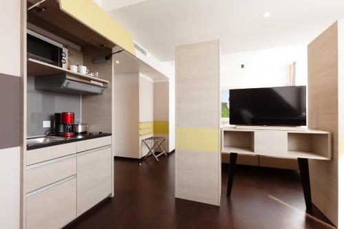 a kitchen with a tv and a desk with a television at Vienna House Easy by Wyndham Osnabrück City & Apartments in Osnabrück