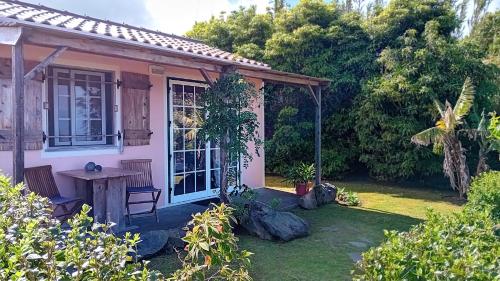a small pink house with a table in a yard at Faial Cottage B&B in Cedros