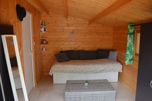 a bedroom with a bed in a wooden cabin at La cabane de Robinson à 500m de la plage in Lacanau