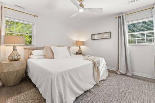 a white bedroom with a bed and two windows at The Gardenia House in Charleston