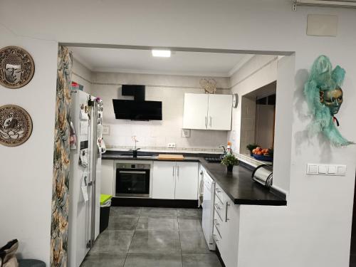 eine Küche mit weißen Schränken und einer schwarzen Arbeitsplatte in der Unterkunft Casa Glori in Vélez-Málaga